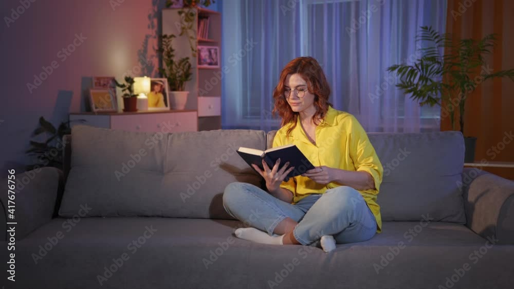 have an idea, young beautiful woman with interesting glasses reads book in evening and shows thumb up while sitting on sofa in cozy apartment have an idea, young beautiful woman with interesting glasses reads book in evening and shows thumb up while sitting on sofa in cozy apartment