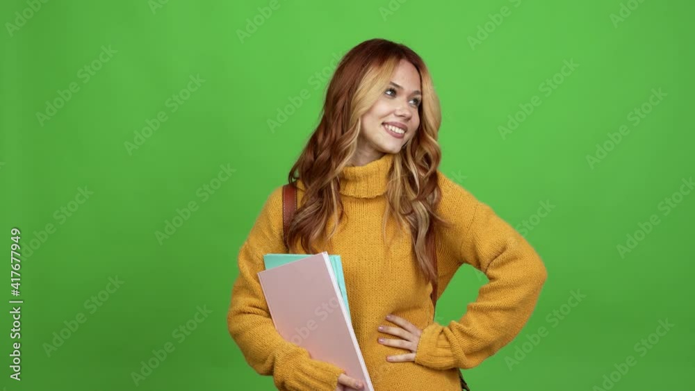 Teenager woman with backpack posing with arms at hip and laughing over isolated background chroma key Teenager woman with backpack posing with arms at hip and laughing over isolated background chroma key