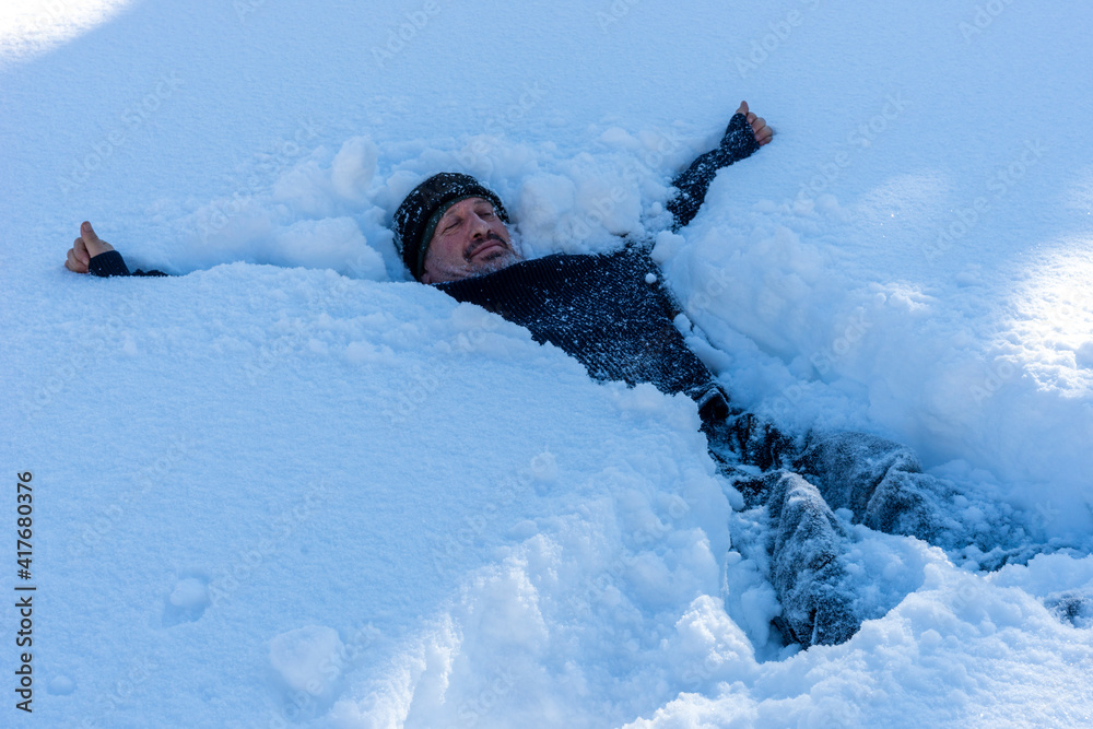 man lying in deep snow in winter season