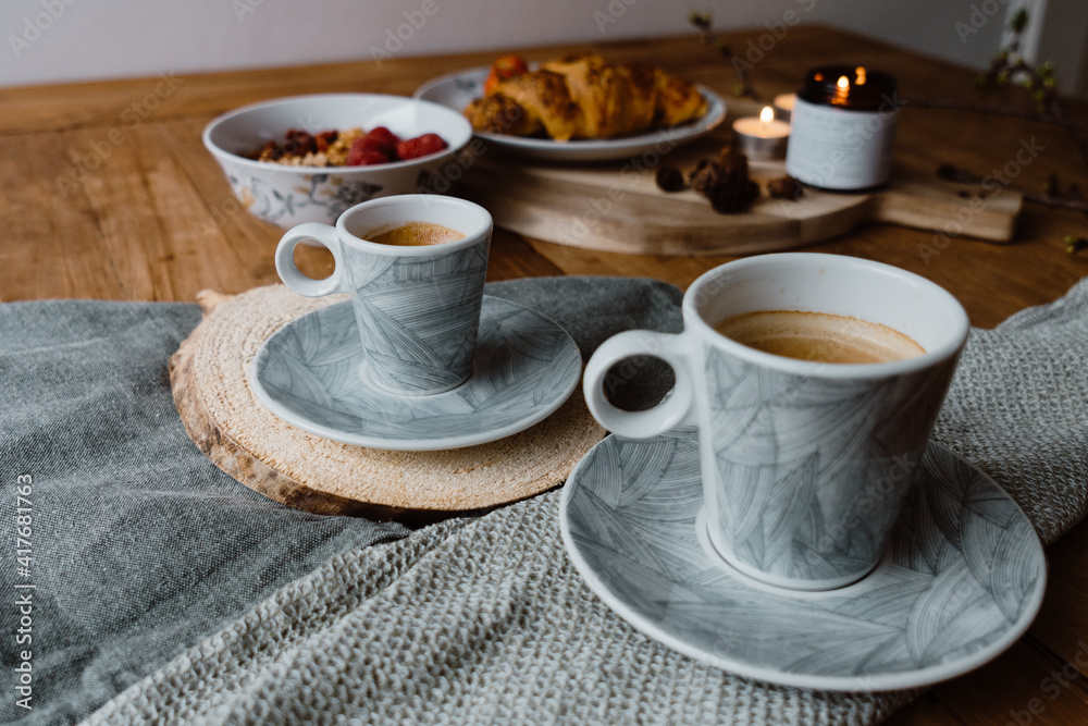 Φωτογραφία Closeup shot of a lighting candle, cups of hot coffee and delicious pastry on a