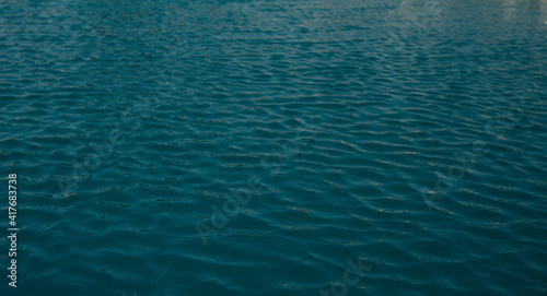 The texture of clear blue water with small waves on a sunny day. Peace and tranquility. Background