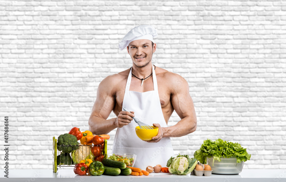 Man bodybuilder in white toque blanche and cook protective apron Man bodybuilder in white toque blanche and cook protective apron