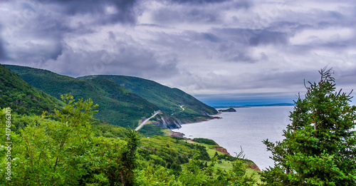 The Cabot Trail winds it's way through the green forested highlands along the ocean shoreline of Cape Breton Island in Nova Scotia Canada.