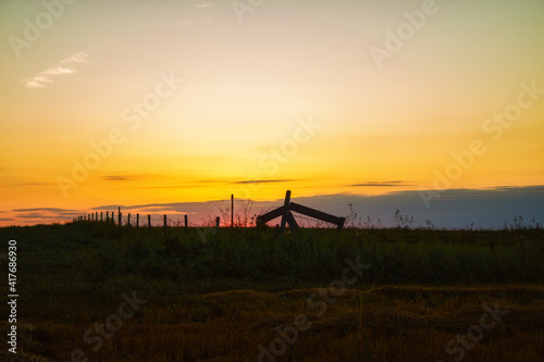 A beautiful orange sunset over a fenced pasture with cut hay in a countryside summer landscape