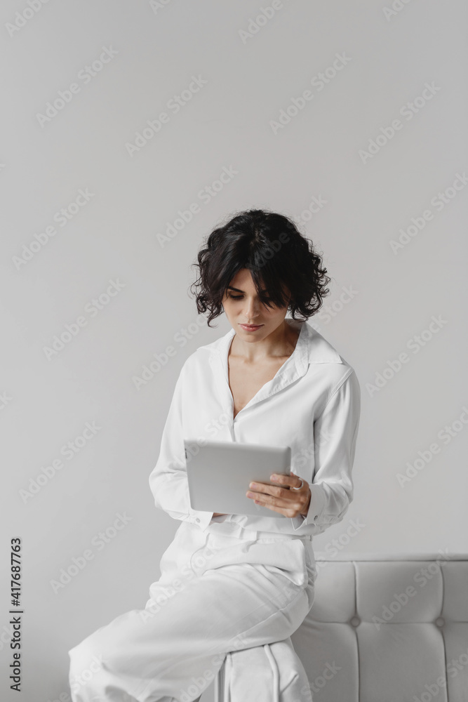 Business woman using digital tablet sitting on sofa in office. Business woman using digital tablet sitting on sofa in office.