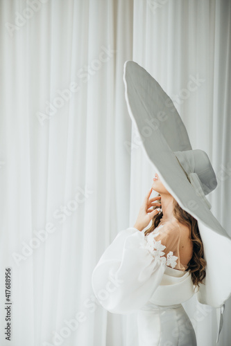 A graceful woman posing with a large wide-brimmed hat.