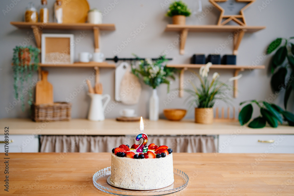 cake with candle number two and fruit on table on Scandinavian-style kitchen cake with candle number two and fruit on table on Scandinavian-style kitchen