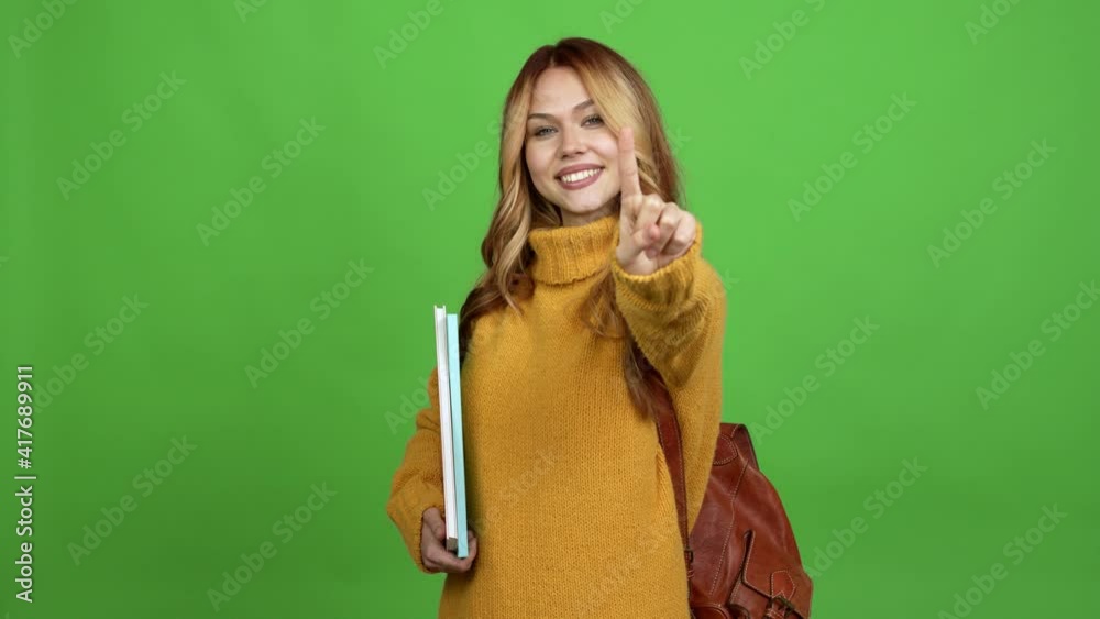 Teenager woman with backpack showing and lifting a finger in sign of the best over isolated background chroma key Teenager woman with backpack showing and lifting a finger in sign of the best over isolated background chroma key