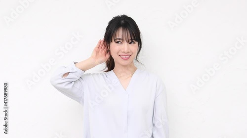 白い壁の前に立って聞き耳を立てる若い女性