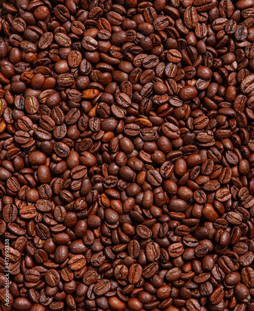 Fototapeta premium Background of roasted brown coffee beans, whole grains for making drinks, contains caffeine. Stylish textured wallpaper