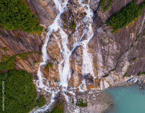 USA, Alaska, Tracy Arm-Fords Terror Wilderness, Waterfall flowing down cliff side along Endicott Arm near Dawes Glacier at dusk on summer evening photo