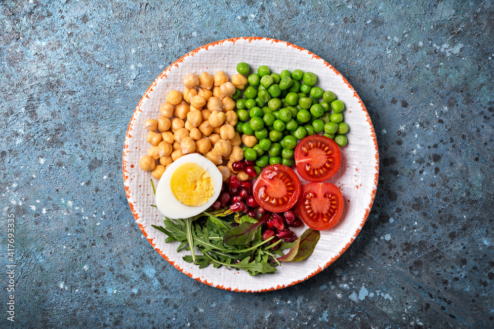 Plakat Talerz zdrowej żywności: ciecierzyca z mieszanką świeżych liści, granat, zielony groszek, pomidorki koktajlowe i jajko na twardo