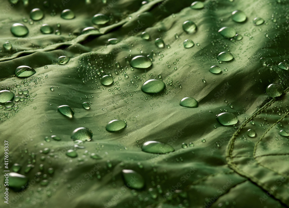 Water drops on waterproof membrane fabric. Detail view of texture of green waterproof cloth. Water drops on waterproof membrane fabric. Detail view of texture of green waterproof cloth.