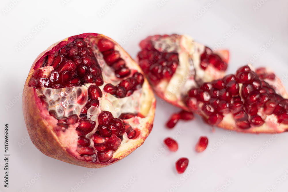 Fresh ripe sliced pomegranate fruit with red seeds isolated on white background Fresh ripe sliced pomegranate fruit with red seeds isolated on white background