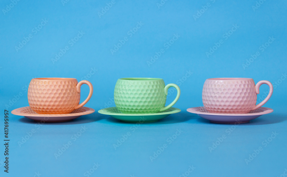 It's coffee time. blue,orange and green coffee cups on the table.blue background. It's coffee time. blue,orange and green coffee cups on the table.blue background.
