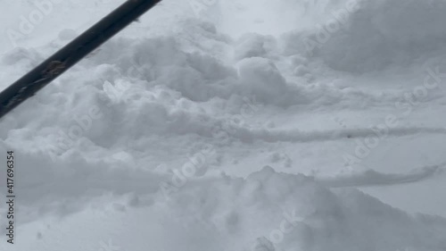 A man in felt boots removes snow with an electric snow plow.	
