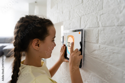 Shot of little girl using a domotic system with her digital tablet while standing at home.