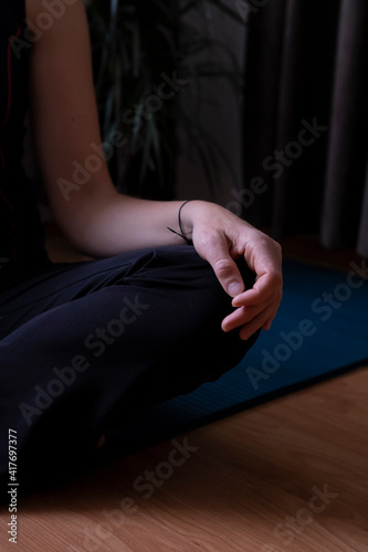 Woman sitting on a blue mat is preparing for yoga.Woman's hand ,lotus position.