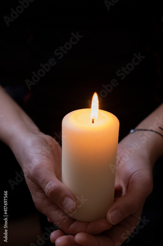 Selective focused young woman holding a candle in her hand.Preparation for a spiritual cleansing ritual in home.