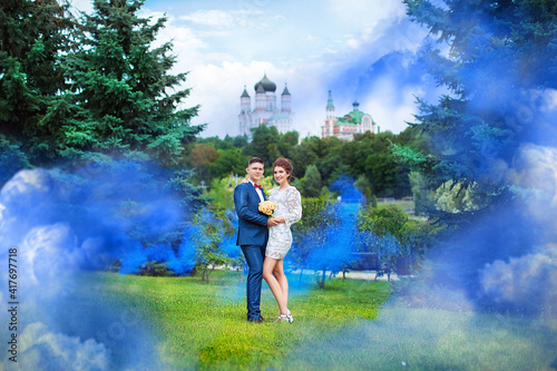 Wedding couple in blue smoke in the park