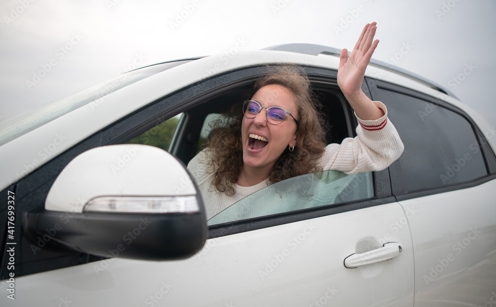 Woman driving very angry sticking her arm out the window in a traffic jam.