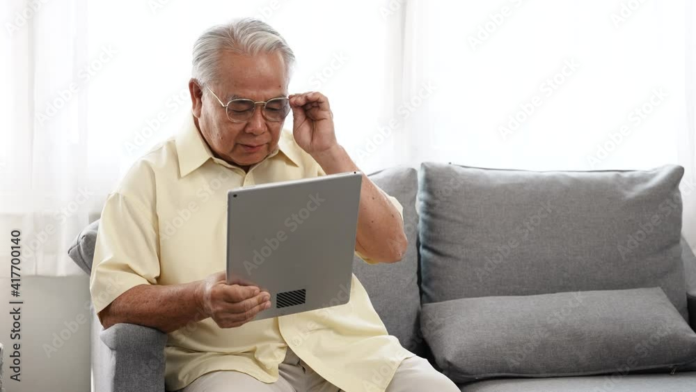 Happy family Little asian daughter surprised grandfather on the sofa with flowers between grandfather watching tablet in the living room, Elderly old man retired enjoy life concept. Happy family Little asian daughter surprised grandfather on the sofa with flowers between grandfather watching tablet in the living room, Elderly old man retired enjoy life concept.