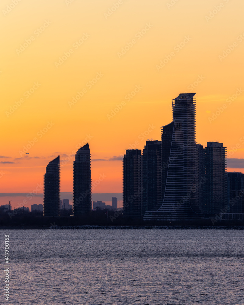 Waterfront apartment building skyline silhouetted in front of a warm vibrant colorful sunset