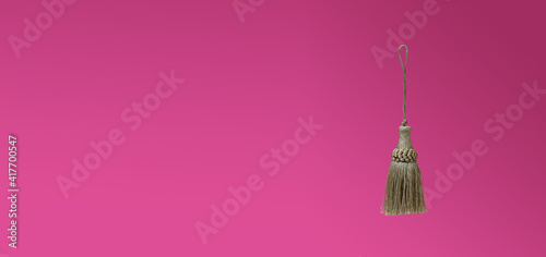Golden silk tassels isolated on pink background for creating graphic concepts © Elena