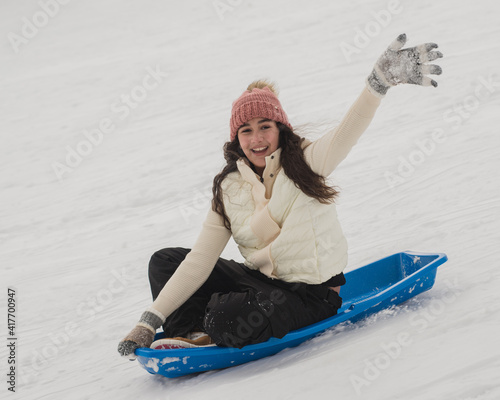 Girl sledding down hill waving