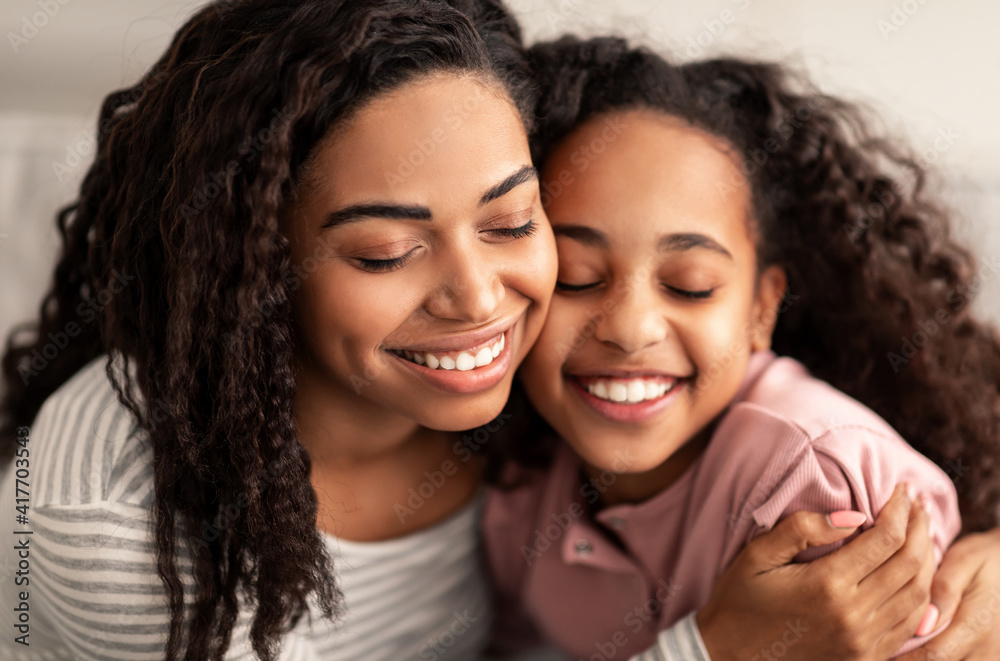 Close up portrait of black mother and daughter hugging Close up portrait of black mother and daughter hugging