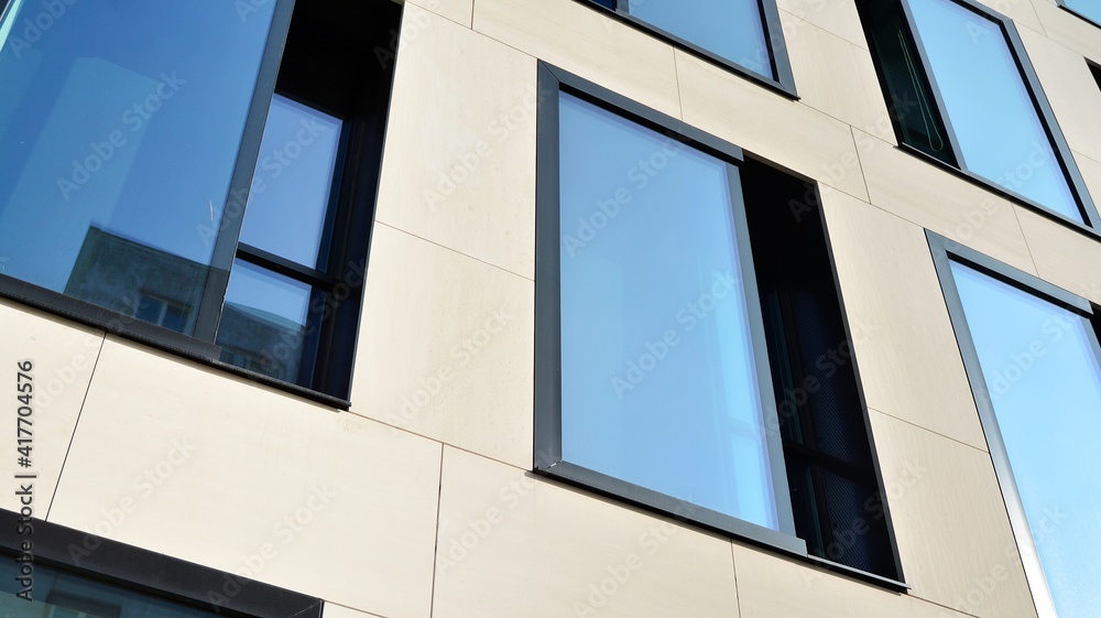 A fragment of the glass and sandstone facade of a modern office building. Wide abstract fragment of modern building facade. View of modern glass and stone facade. A fragment of the glass and sandstone facade of a modern office building. Wide abstract fragment of modern building facade. View of modern glass and stone facade.