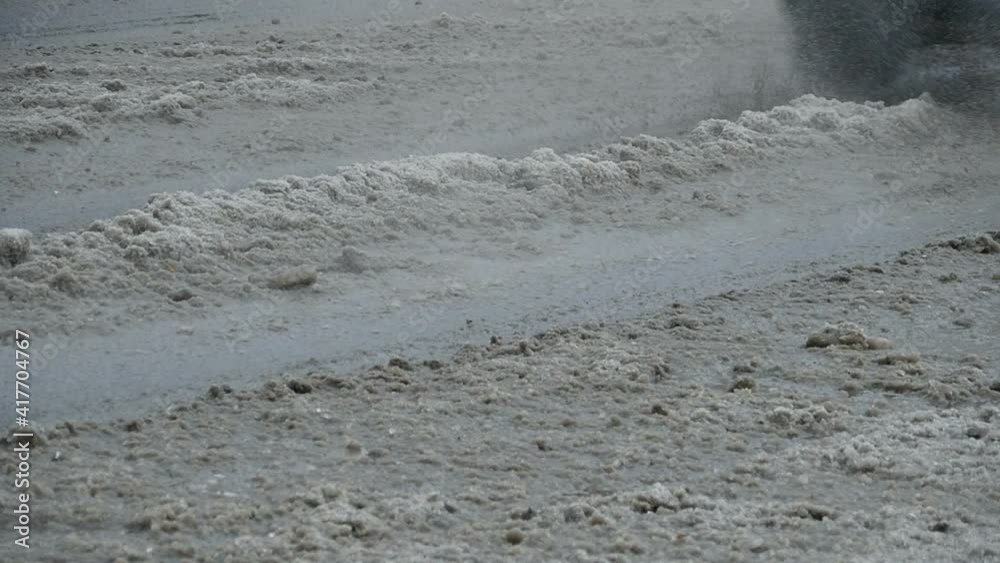 melt water splashes from a car wheel a passing car slow motion