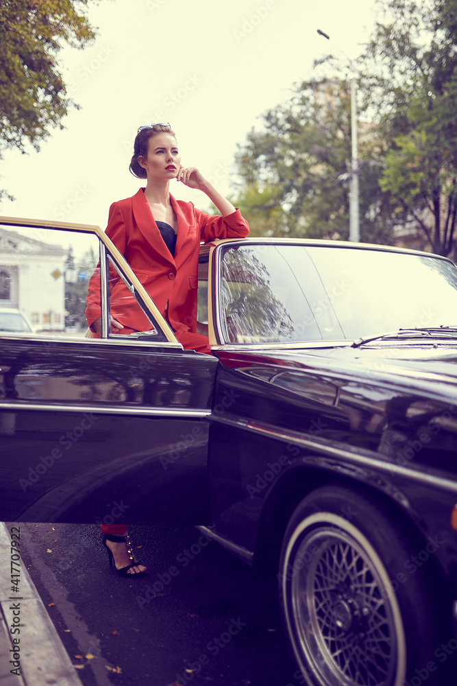 Beautiful young woman wearing red costume while standing near retro car