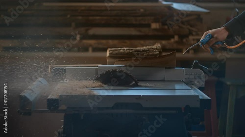 Carpenter blows wood shavings off a circular saw machine with a pneumatic gun in slow motion, sawdust at woodworking workshop, Full HD 240p Prores 422 10 bit photo