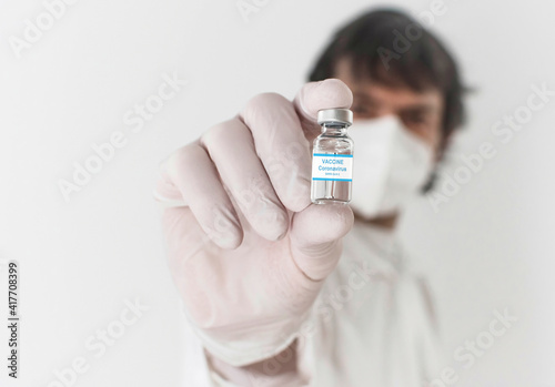 Doctor holding a vaccine bottle and syringe, beginning of worldwide mass vaccination for coronavirus COVID-19, influenza or flu, world immunization concept. Selective focus