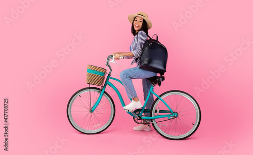 Asian lady riding retro bicycle with wicker basket © Prostock-studio