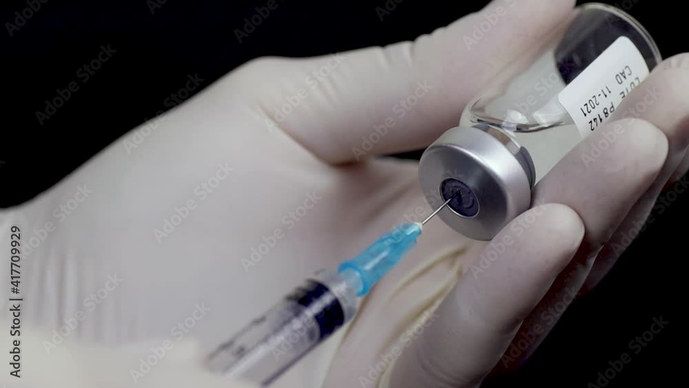 Manos en guantes llenando jeringuilla para inyección de vacuna