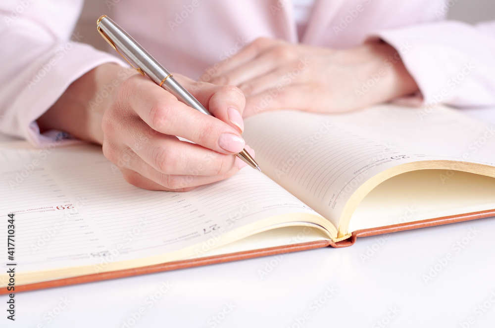a woman writes down information with a pen in a diary a woman writes down information with a pen in a diary