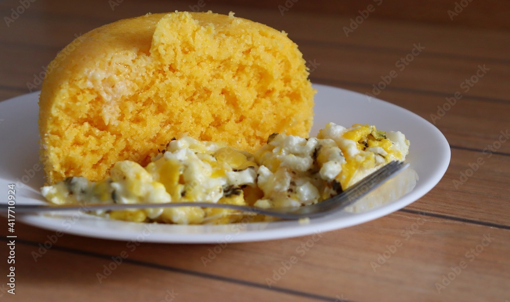 Brazilian couscous and scrambled eggs (Cuscuz com ovo) on wooden background. Typical Couscous of Northeast of Brazil. Brazilian couscous and scrambled eggs (Cuscuz com ovo) on wooden background. Typical Couscous of Northeast of Brazil.