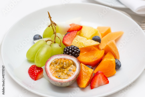 Fruit plate of fresh fruit slices for breakfast. On a white plate, passionfruit,