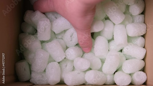 female hand is sorting polypropylene balls for packing fragile parcels in a cardboard box, psychological satisfying, Stress Squeeze, concept of postal item, package, buying goods online