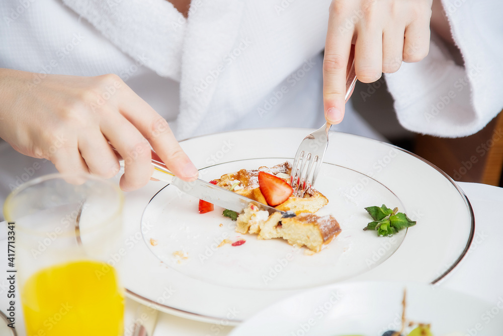 Cropped photo of a man in a white terry dressing gown having a breakfast