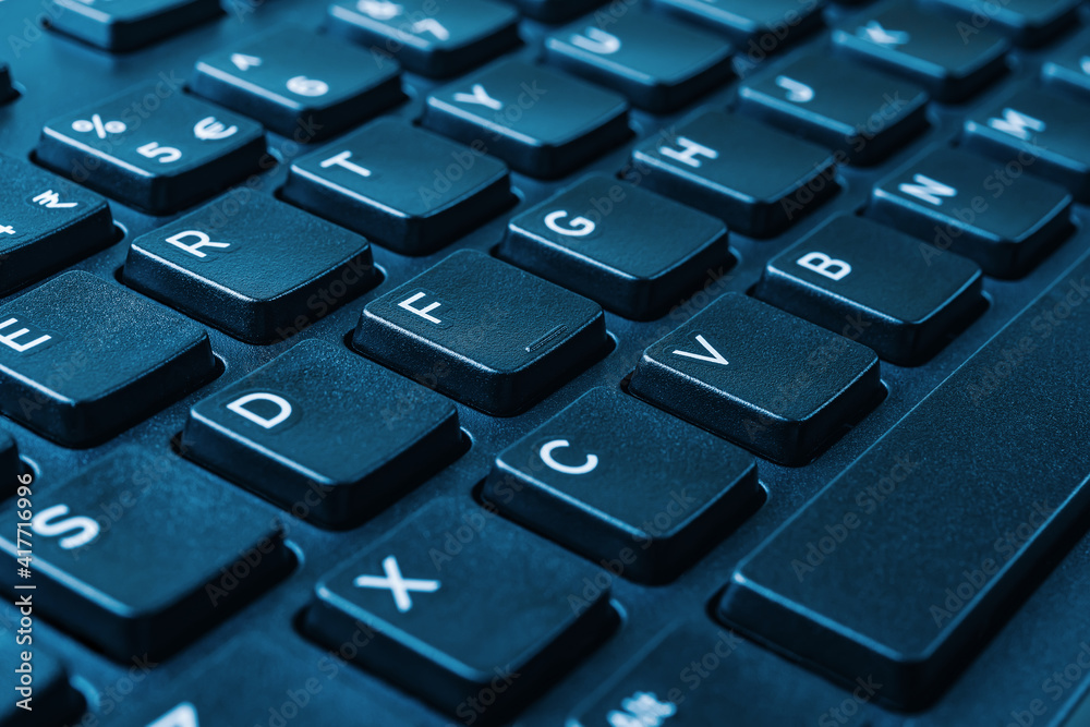 Closeup of the black computer keyboard on blue tone. Distance learning, online work, business and shopping, confirm product order or agreement concepts. Macro shot. Closeup of the black computer keyboard on blue tone. Distance learning, online work, business and shopping, confirm product order or agreement concepts. Macro shot.