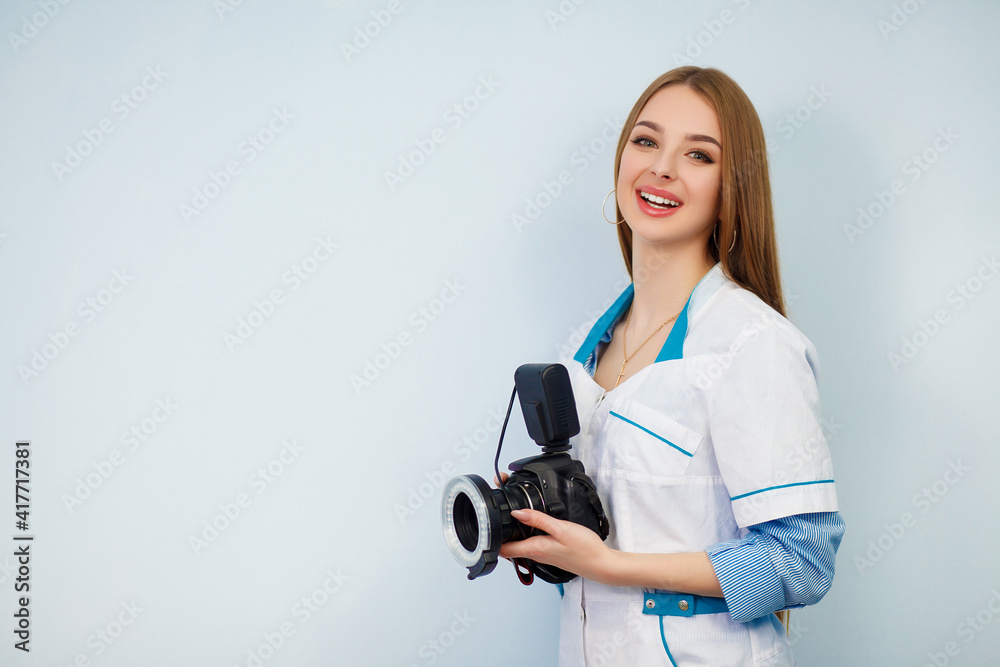 Image of a woman doctor isolated over white wall background. Dentist with a camera in hand. Copy space. Beautiful girl in a white coat Image of a woman doctor isolated over white wall background. Dentist with a camera in hand. Copy space. Beautiful girl in a white coat