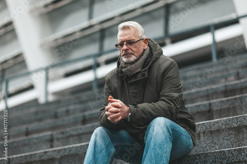 Fototapeta Naklejka Na Ścianę i Meble -  Prayer to God. An elderly man sits outdoors hoping. Thinks alone, depressed.