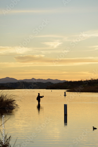 USA  Arizona  Patagonia Lake State Park. Backlit man fishing at sunset