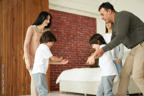 Joyful latin children, little twin boys smiling while having fun with their sister and parents indoors. Mom and dad playing with their kids at home © Friends Stock