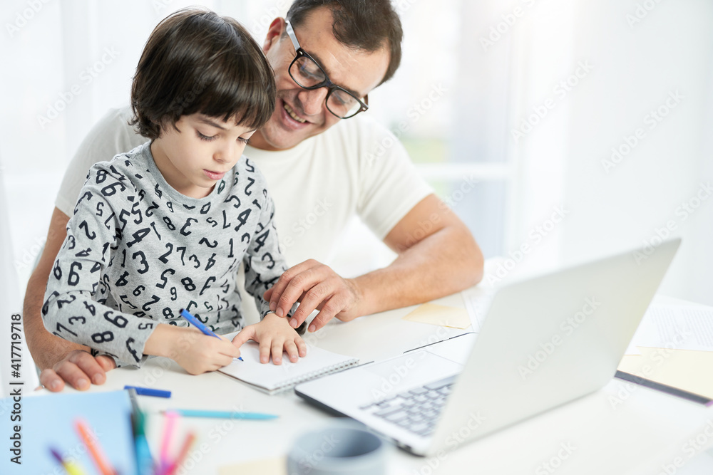 Develop a passion for learning. Cute little latin son spending time with his father at home. Businessman using laptop while working from home during lockdown and watching child Develop a passion for learning. Cute little latin son spending time with his father at home. Businessman using laptop while working from home during lockdown and watching child