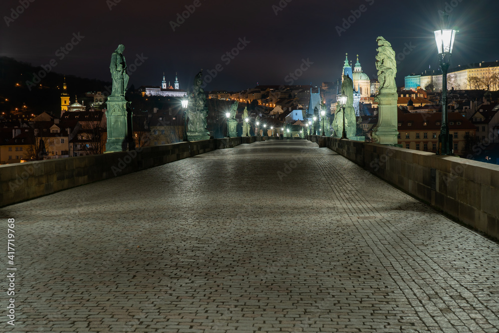 Obraz premium view of statues on Charles Bridge originally from the 17th century and light from lanterns and in the background Prague Castle and St. Vitus Cathedral in the center of Prague at night