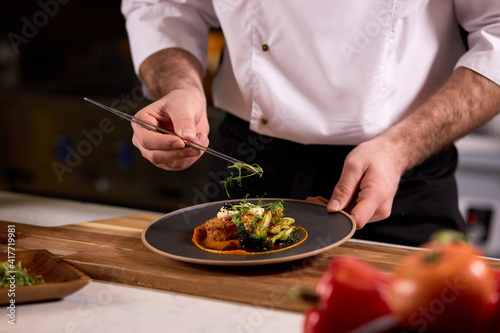 Canvastavla chef dressing salad with fresh greens, adding finishing touch on dish before it